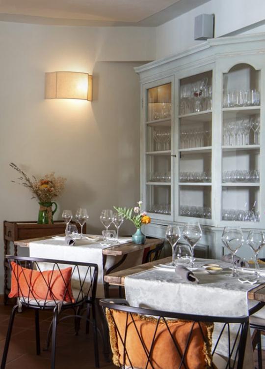 Ristorante accogliente con tavoli apparecchiati, arco in mattoni e mobili rustici.