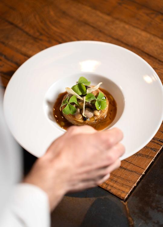 Piatto gourmet con verdure fresche e salsa, servito su un tavolo di legno.