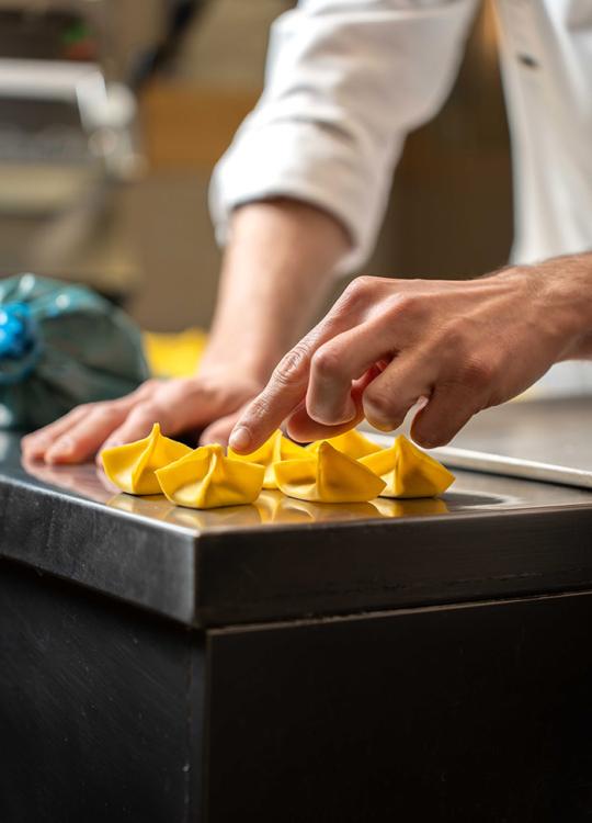 Preparazione di pasta fresca ripiena su un piano di lavoro in cucina.